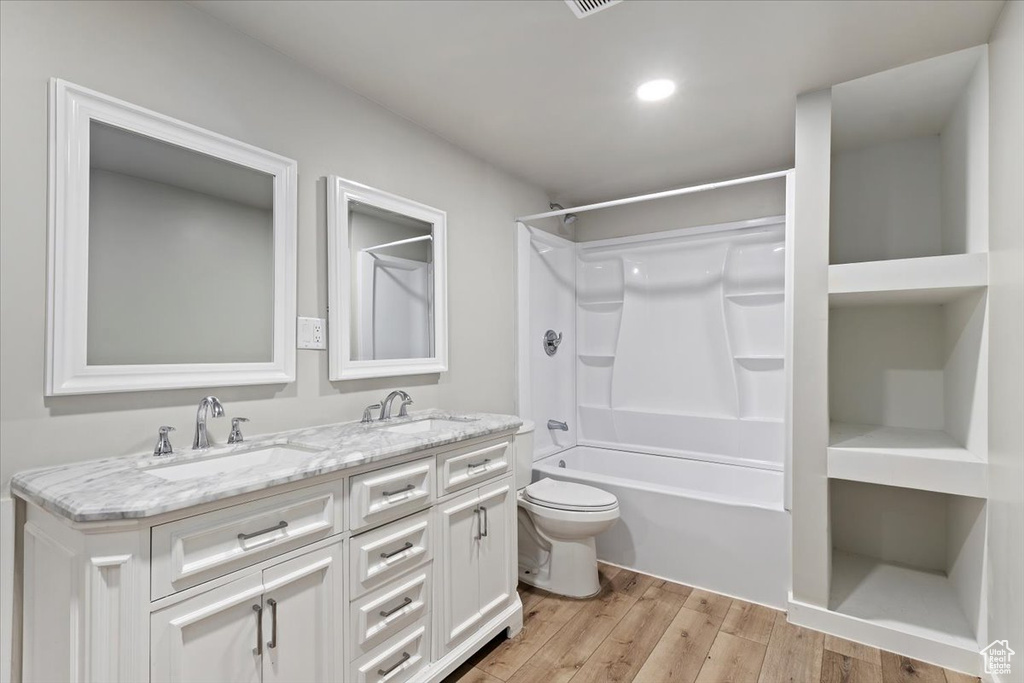 Bathroom with double vanity, wood finished floors, shower / bathtub combination, and recessed lighting