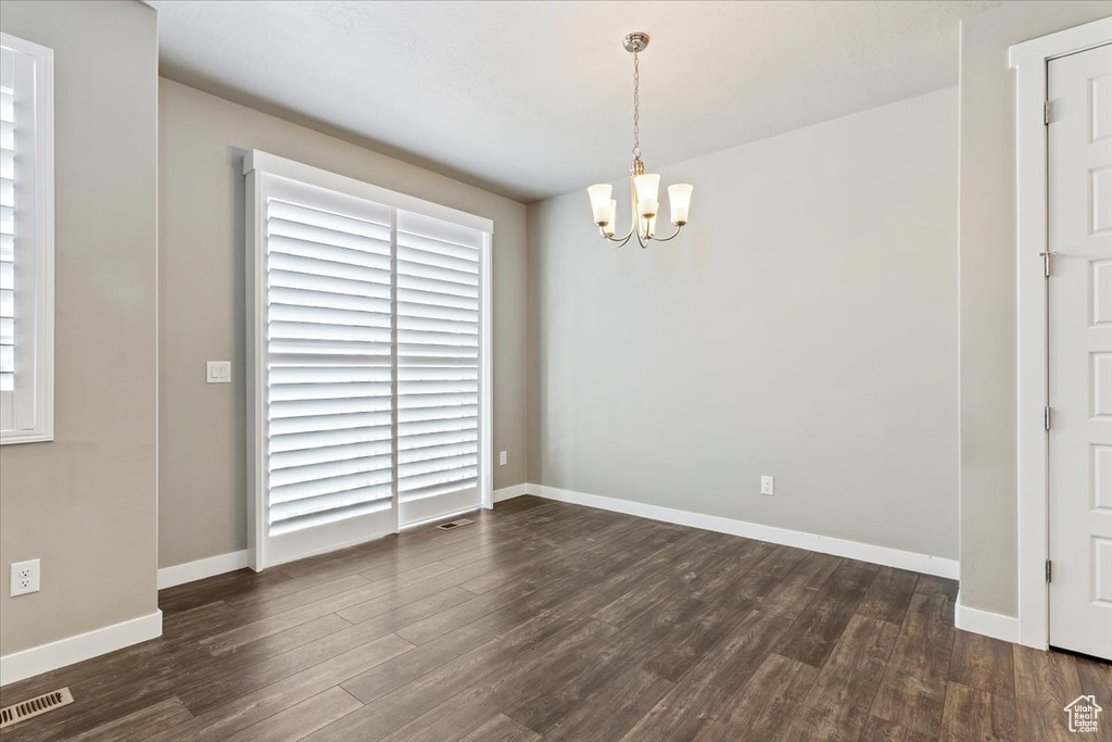 Unfurnished room with a chandelier and dark wood-style flooring
