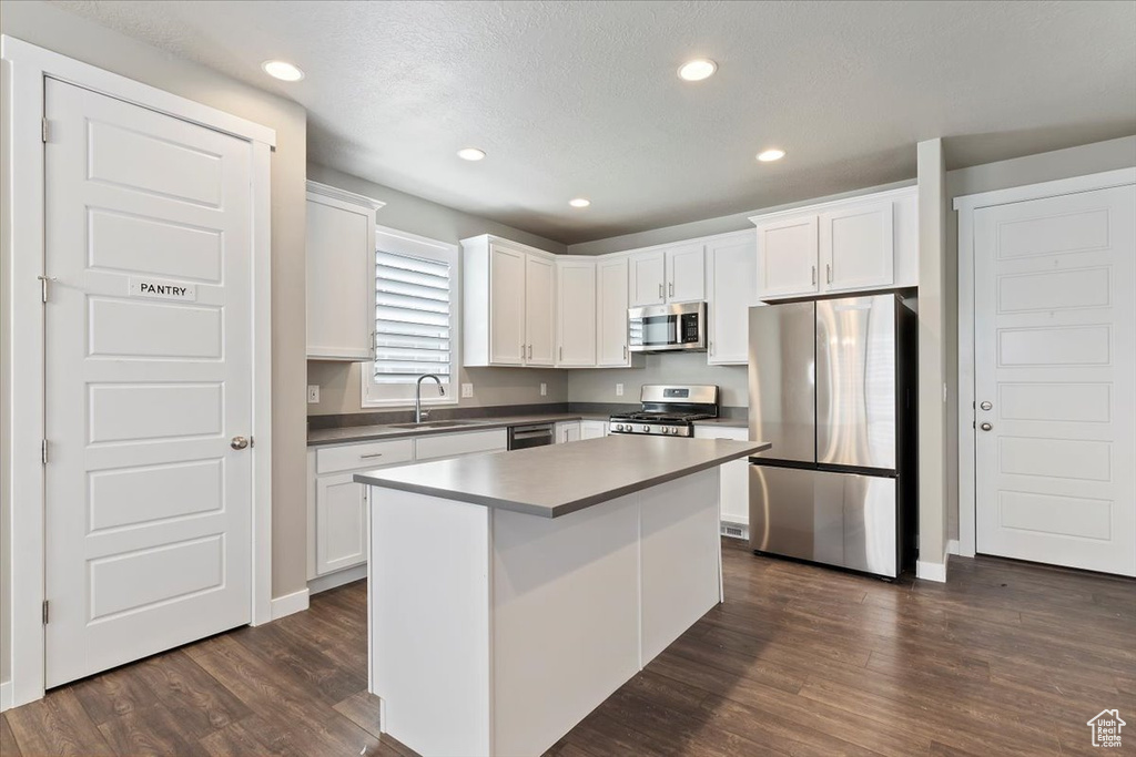 Kitchen featuring stainless steel appliances, dark wood-style flooring, white cabinetry, a kitchen island, and recessed lighting