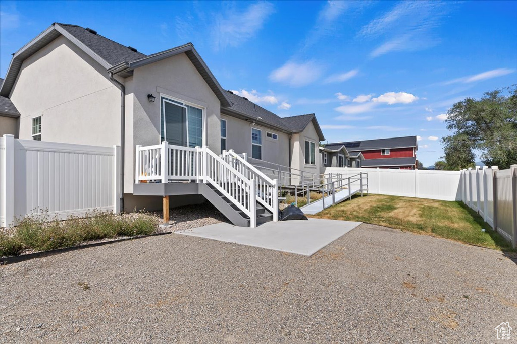 Rear view of property featuring a fenced backyard, stucco siding, a patio area, and a shingled roof