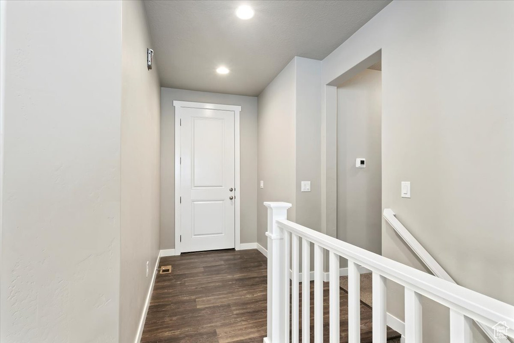 Hallway featuring an upstairs landing, dark wood-style floors, and recessed lighting