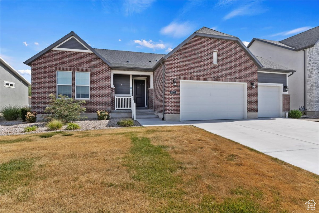 View of front of house with a garage, concrete driveway, brick siding, and a front lawn