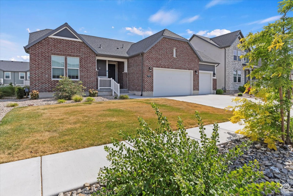 View of front of property featuring brick siding, a garage, a front lawn, and concrete driveway