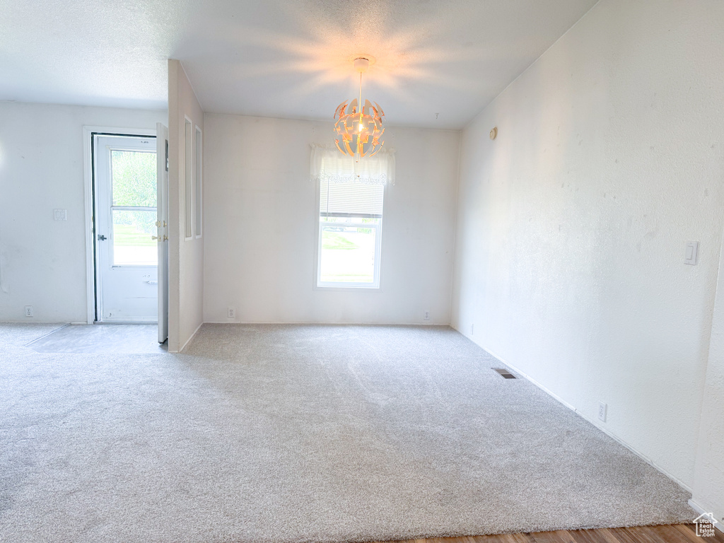 Carpeted empty room featuring a chandelier
