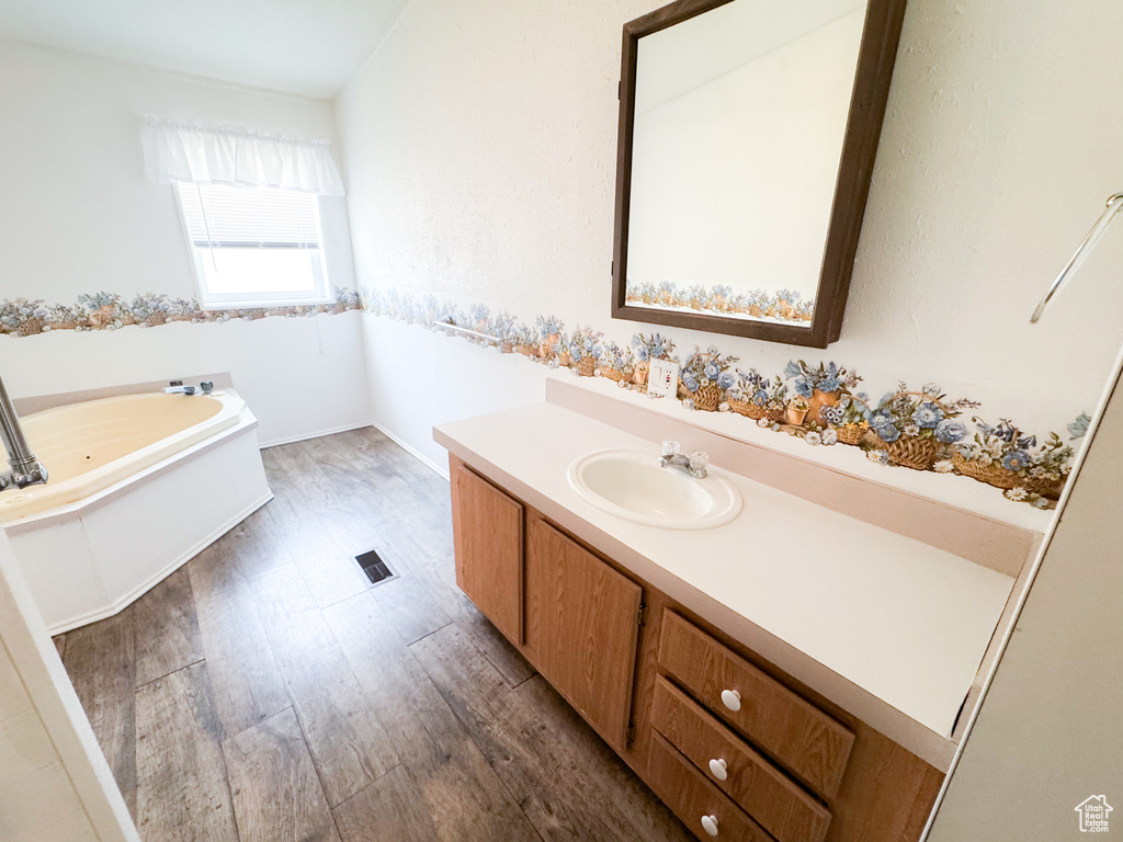 Full bath featuring vanity, a whirlpool tub, and wood finished floors