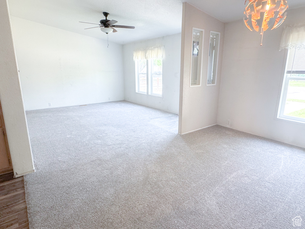Unfurnished room featuring healthy amount of natural light, carpet, and a ceiling fan