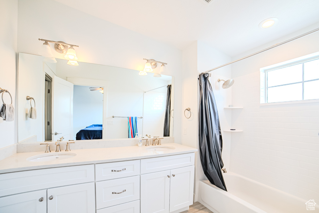 Bathroom featuring shower / tub combo with curtain, double vanity, ensuite bathroom, and a ceiling fan