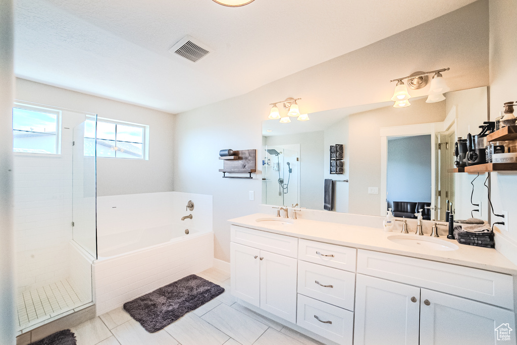 Bathroom with a bath, double vanity, and a tile shower