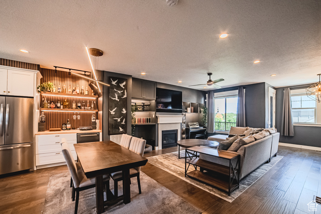Living room with a textured ceiling, dark wood finished floors, plenty of natural light, a glass covered fireplace, and recessed lighting