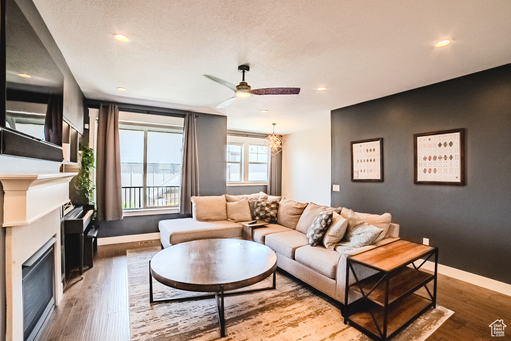 Living room featuring a fireplace, wood finished floors, recessed lighting, ceiling fan, and a textured ceiling