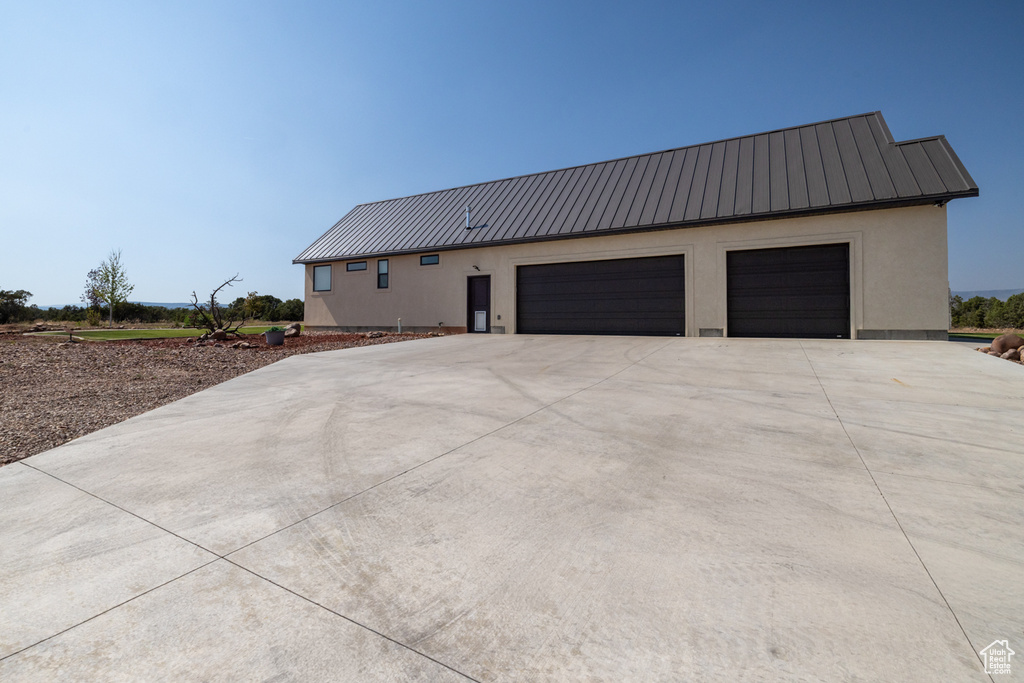 View of front of house with a metal roof, driveway, an attached garage, and a standing seam roof