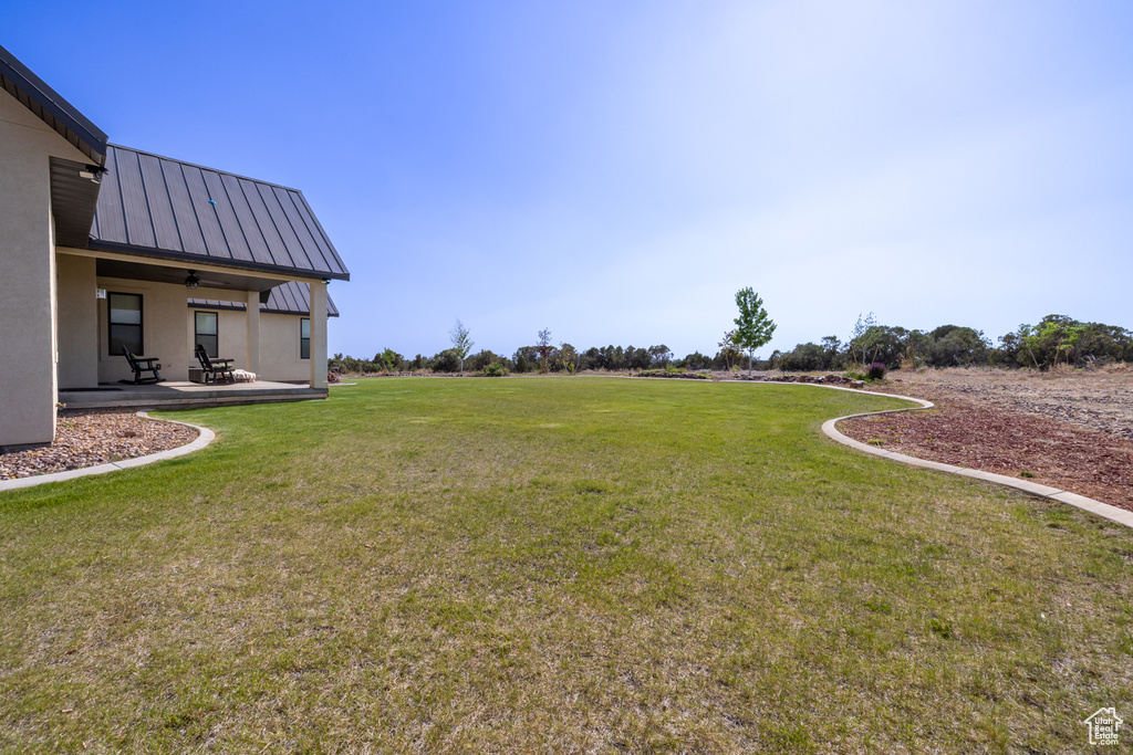View of green lawn with a patio and a ceiling fan