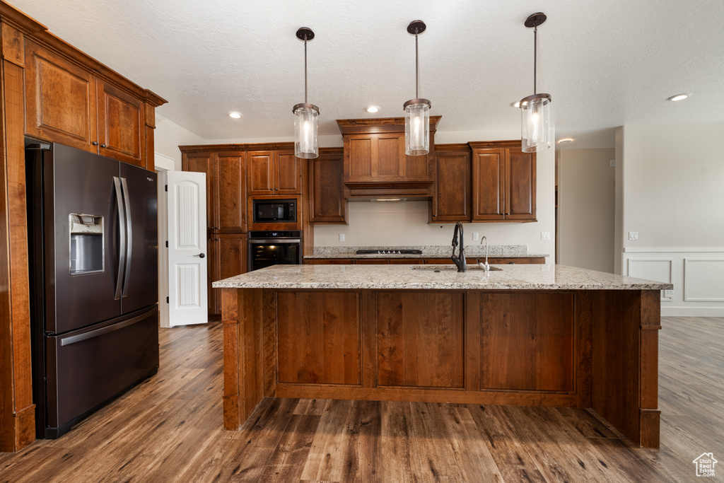 Kitchen featuring appliances with stainless steel finishes, recessed lighting, a kitchen island with sink, dark wood finished floors, and pendant lighting