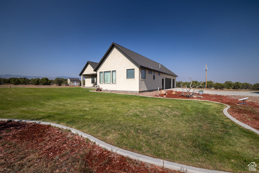 View of side of property featuring a lawn and stucco siding