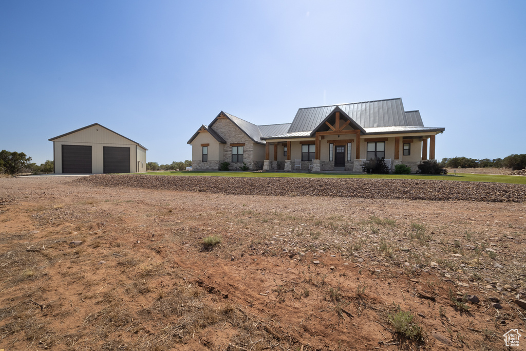 Modern farmhouse style home with a detached garage, an outbuilding, stone siding, and a metal roof
