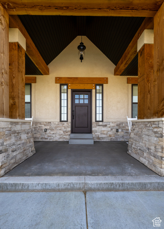View of exterior entry featuring stone siding, stucco siding, and covered porch