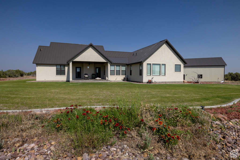 Back of property featuring a metal roof, a lawn, a patio area, and stucco siding