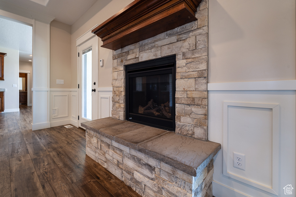 Detailed view of wood finished floors, wainscoting, a fireplace, and a decorative wall