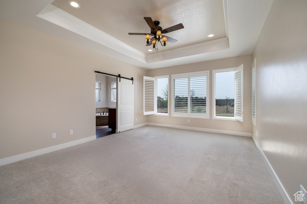 Spare room featuring a raised ceiling, carpet, plenty of natural light, recessed lighting, and a ceiling fan