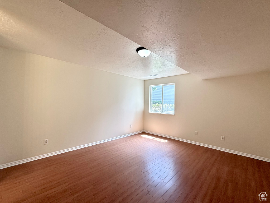 Spare room with a textured ceiling and dark wood finished floors