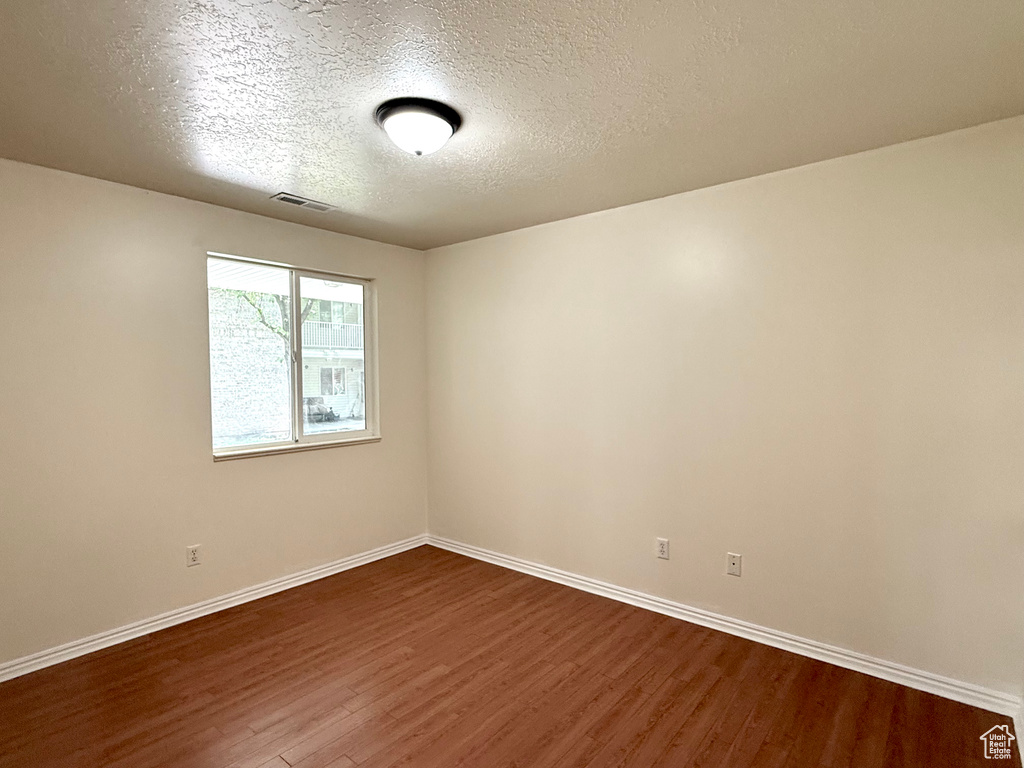 Empty room with dark wood-style floors and a textured ceiling