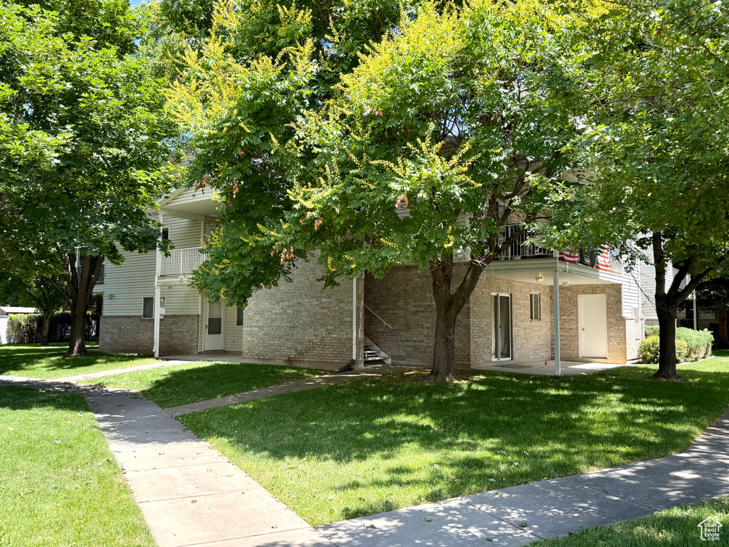 Obstructed view of property with brick siding and a front lawn