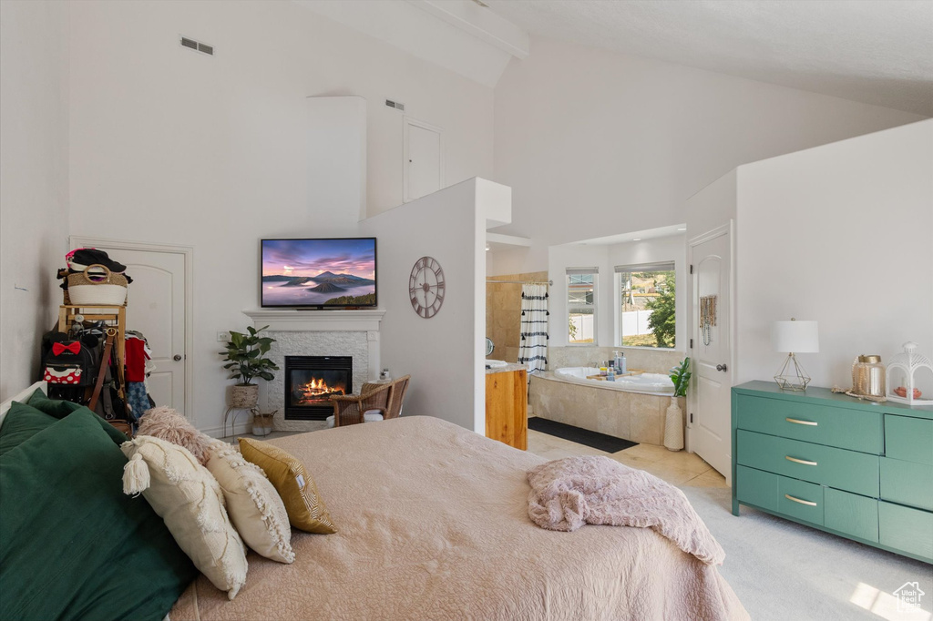 Bedroom featuring high vaulted ceiling, a glass covered fireplace, beam ceiling, and light carpet