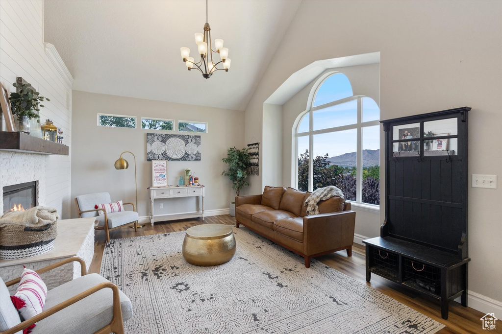 Living room with a mountain view, high vaulted ceiling, a chandelier, wood finished floors, and a fireplace