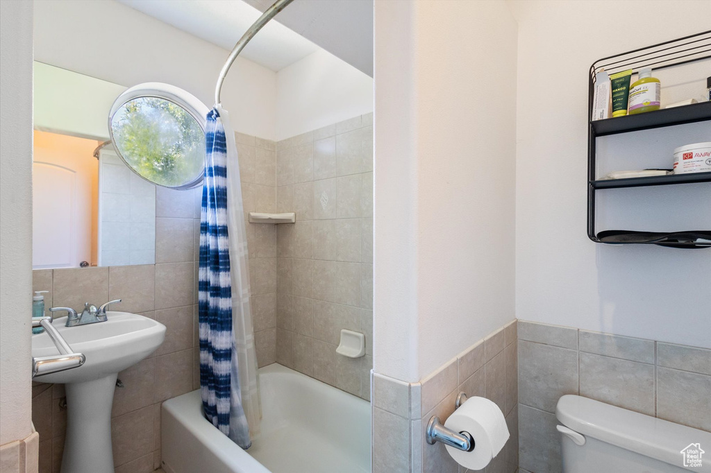 Full bath with tile walls and shower / bath combo with shower curtain