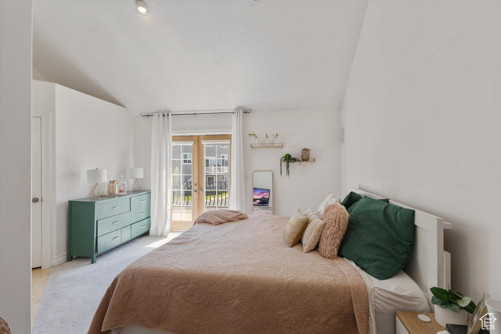 Bedroom with access to exterior, french doors, light carpet, and lofted ceiling
