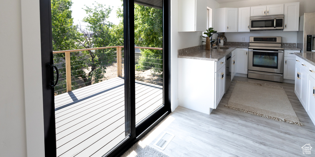 Kitchen with stainless steel appliances, plenty of natural light, and white cabinetry