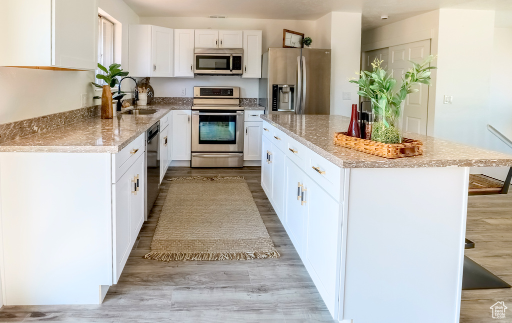 Kitchen with appliances with stainless steel finishes, white cabinetry, and light wood-type flooring