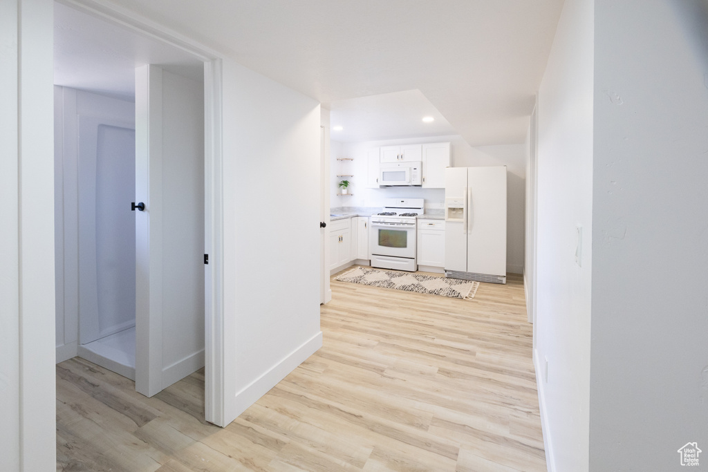 Kitchen with white appliances, light wood-style flooring, white cabinetry, open shelves, and recessed lighting