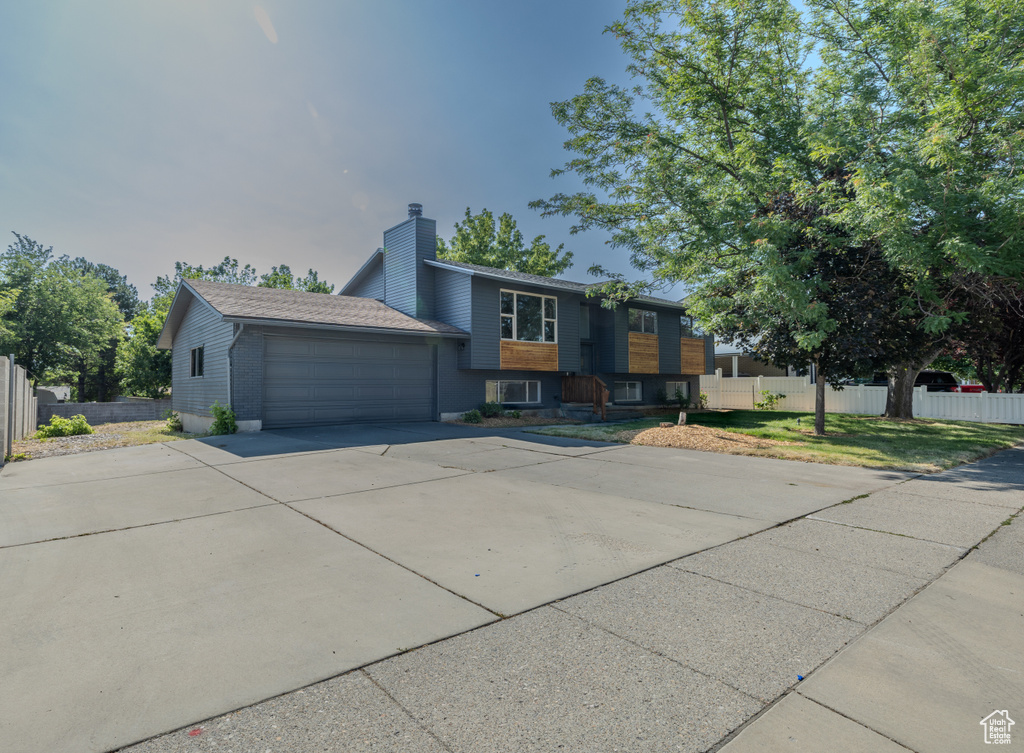 View of front of property featuring a chimney, an attached garage, concrete driveway, and brick siding