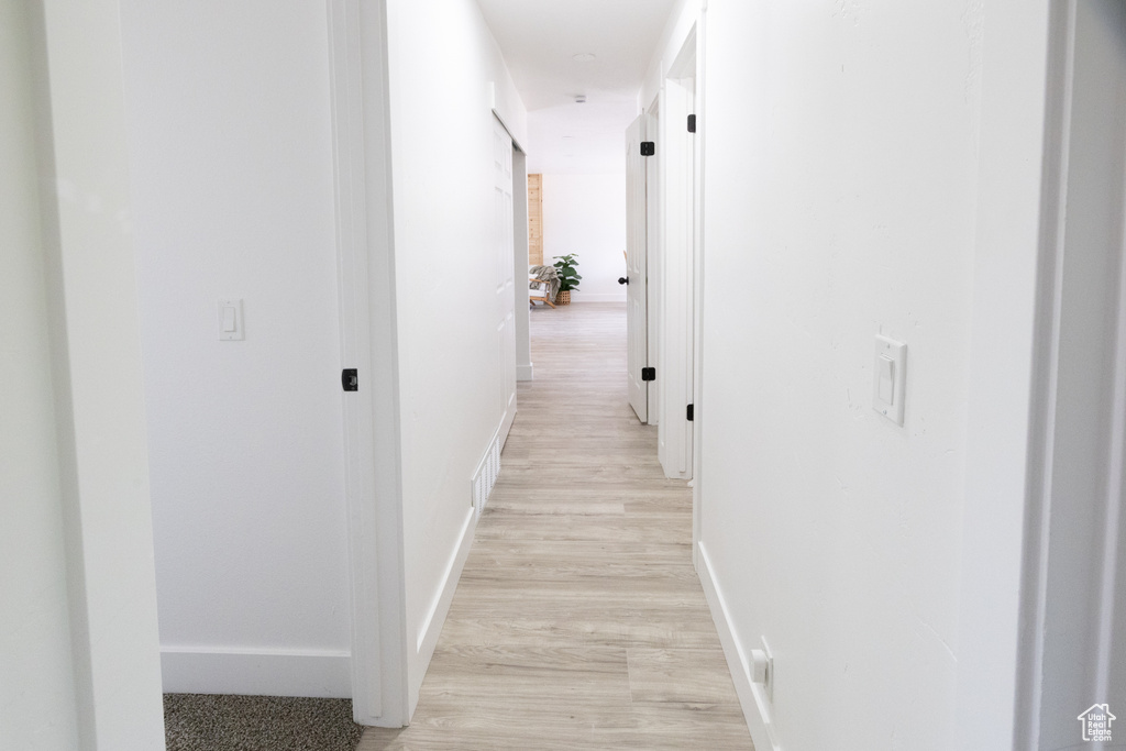 Corridor with light wood-style flooring and baseboards