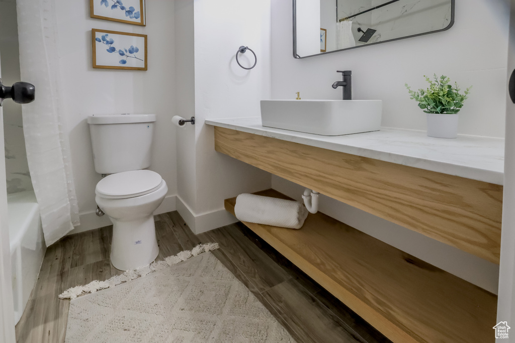 Bathroom with wood finished floors, vanity, and shower / tub combo