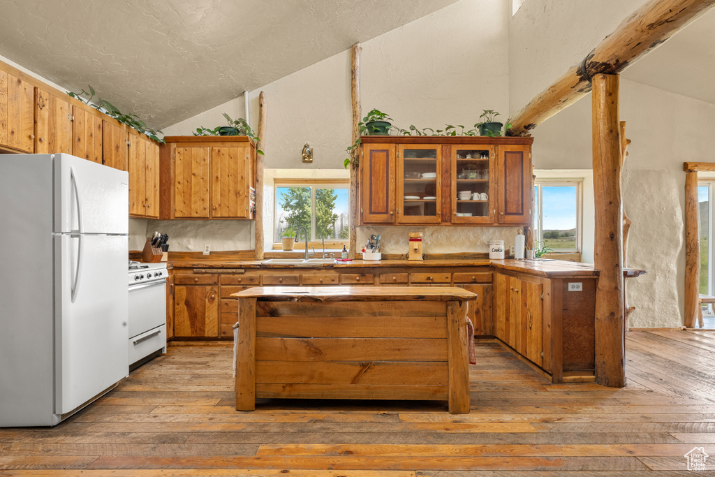 Kitchen with white appliances, lofted ceiling, light wood-style flooring, brown cabinets, and backsplash