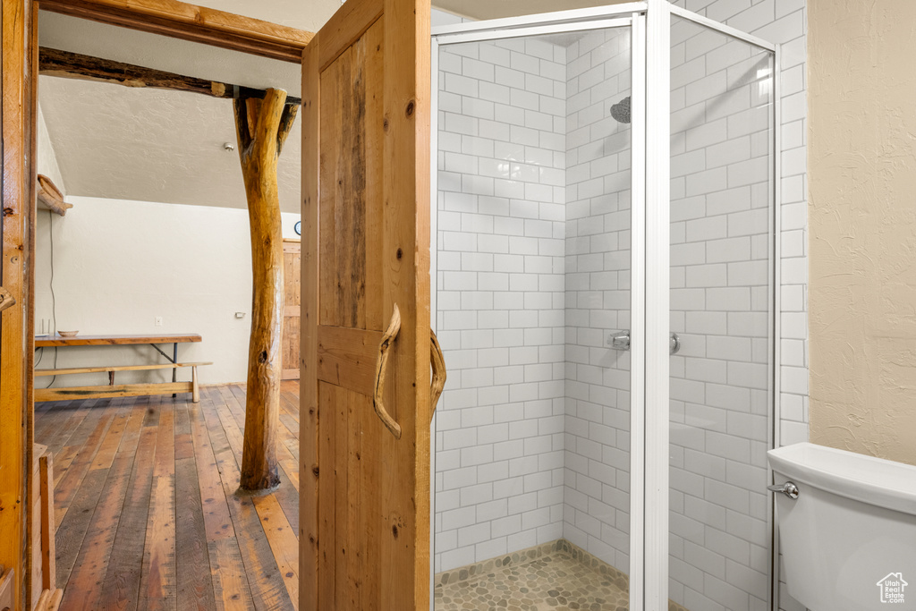 Full bath with a shower stall, hardwood / wood-style flooring, and a textured wall