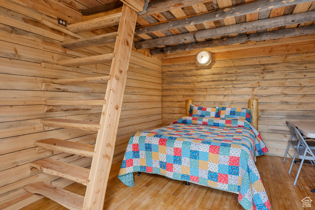 Bedroom with hardwood / wood-style flooring and wood walls