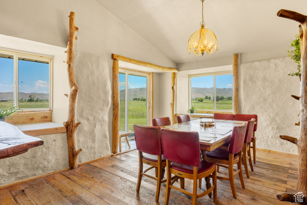 Dining room featuring vaulted ceiling, light wood finished floors, a chandelier, and a mountain view