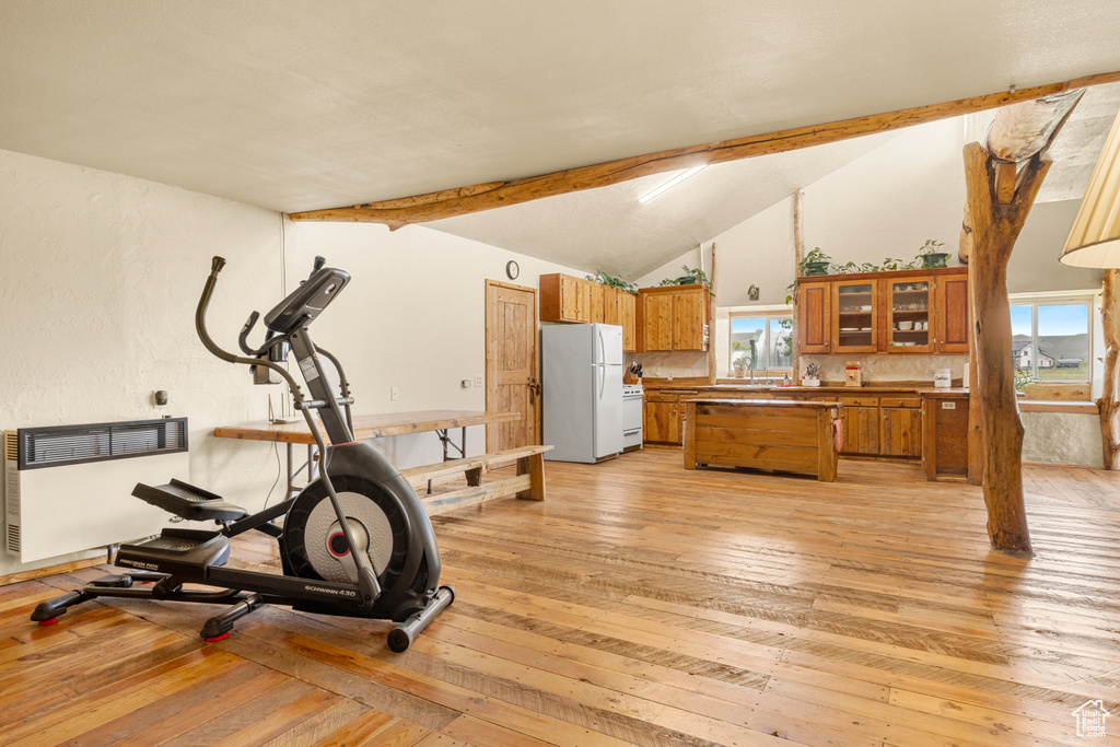Workout room with light wood finished floors, lofted ceiling, and radiator