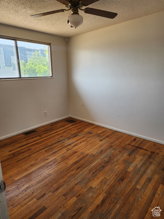 Spare room featuring ceiling fan, dark wood finished floors, and a textured ceiling