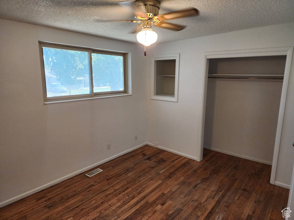 Unfurnished bedroom with dark wood finished floors, a closet, a textured ceiling, and ceiling fan