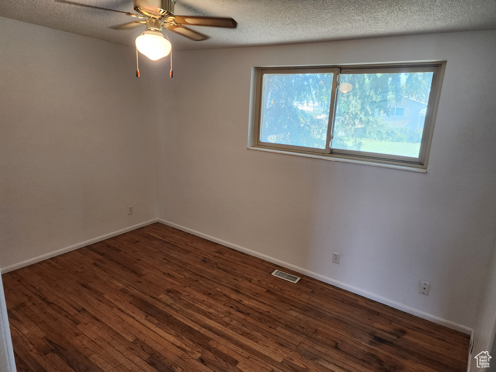 Unfurnished room featuring dark wood-style floors, a ceiling fan, and a textured ceiling