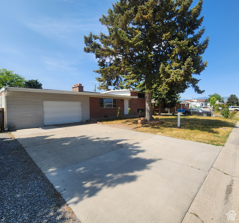 Split level home featuring an attached garage, concrete driveway, and a chimney