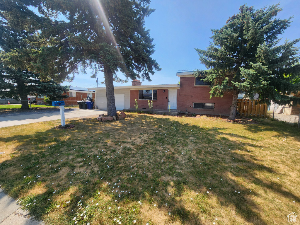 Tri-level home featuring driveway, an attached garage, and a chimney