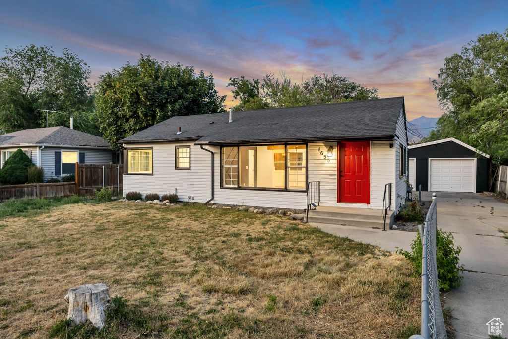 Single story home featuring an outdoor structure, a garage, concrete driveway, and roof with shingles