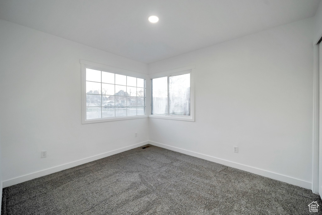 Unfurnished room with dark colored carpet and recessed lighting