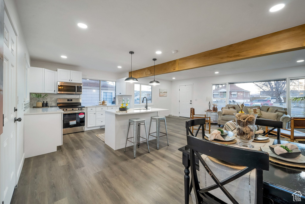 Kitchen with appliances with stainless steel finishes, open floor plan, recessed lighting, white cabinets, and light countertops