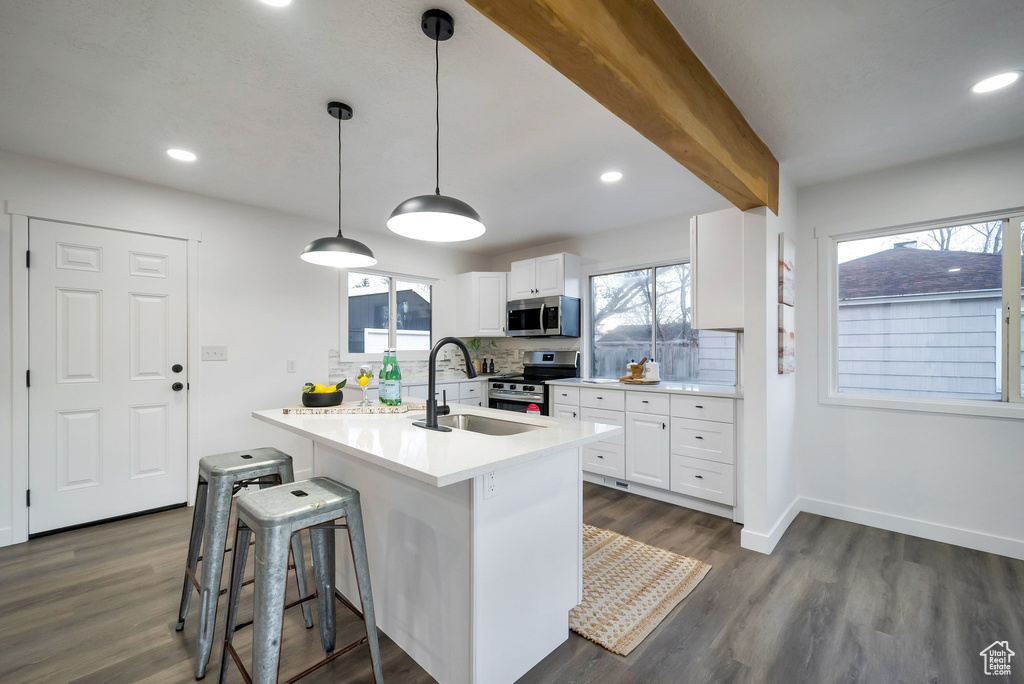 Kitchen with appliances with stainless steel finishes, plenty of natural light, dark wood-style flooring, white cabinetry, and recessed lighting